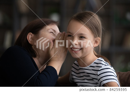 Close up happy grandmother with little granddaughter gossiping, sharing secrets 84259395