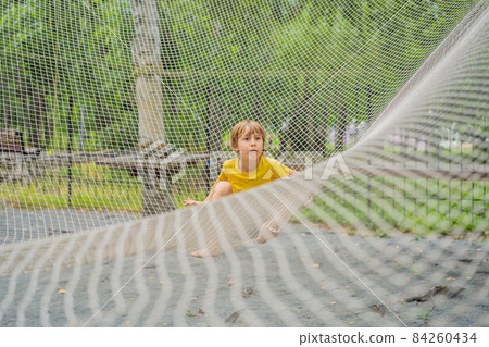practice nets playground. boy plays in the playground shielded with a protective safety net. concept of children on line, kid in social networks. blurred background, blurred motion due to the concept practice nets playground. boy plays in the playground shielded with a protective safety net. concept of children on line, kid in social networks. blurred background, blurred motion due to the concept 84260434