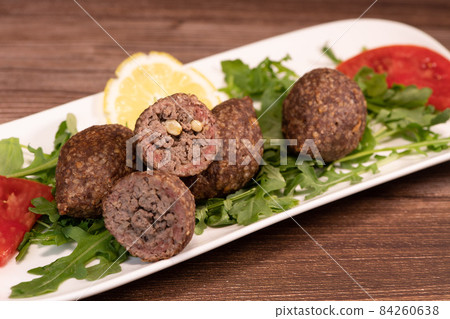 Traditional kebbe and pita bread on big round plate in lebanese restaurant Traditional kebbe and pita bread on big round plate in lebanese restaurant 84260638