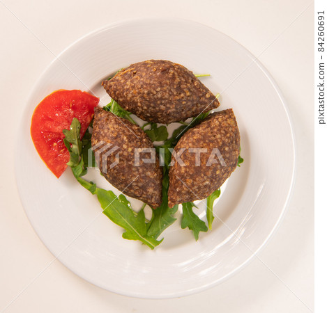 Traditional kebbe and pita bread on big round plate in lebanese restaurant Traditional kebbe and pita bread on big round plate in lebanese restaurant 84260691