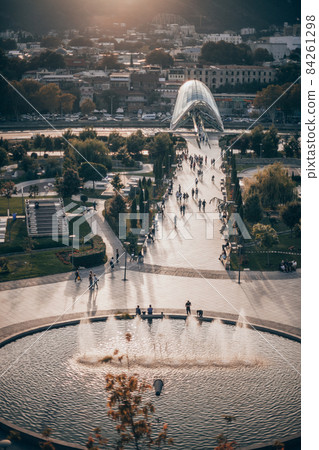 City view with modern and ancient buildings in Georgia. Modern art park with round fountain on the sunset. New architecture in Europe. High quality 84261298