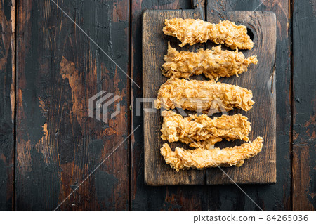 Fried crispy chicken stripes on old dark wooden table, top view, with copy space Fried crispy chicken stripes on old dark wooden table, top view, with copy space 84265036
