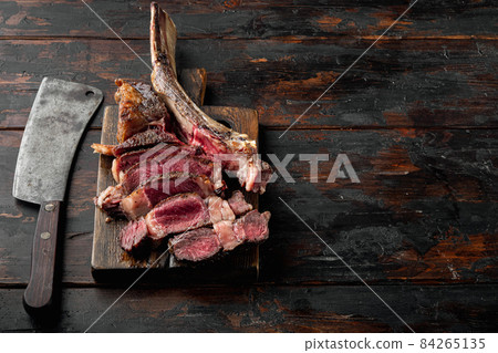Medium rare Tomahawk meat marbled dry aged beef grilled, on wooden serving board, on old dark wooden table background, with copy space for text 84265135