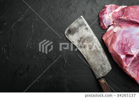 Raw meat, piece of pork , with old butcher cleaver knife, on black dark stone table background, top view flat lay, with copy space for text 84265137