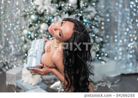 Beautiful nude woman posing against the backdrop of Christmas decorations. 84266288