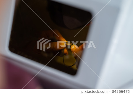 The technician solders the metal frame of the glasses. The technician solders the metal frame of the glasses. 84266475