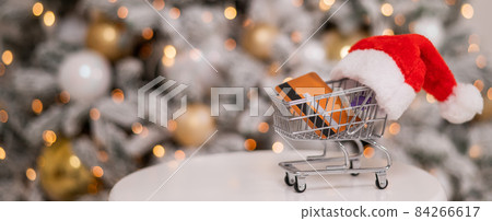 Christmas gifts shopping concept. Credit card in the shopping cart by the christmas tree. 84266617