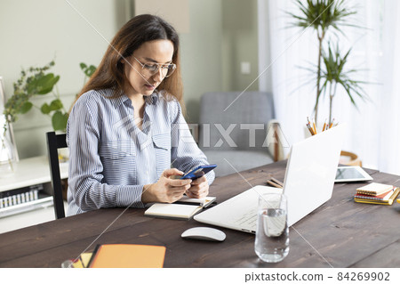 Freelancer young woman messaging with phone at home. 84269902