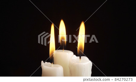 Photo of the burning a three candles on black background 84270273