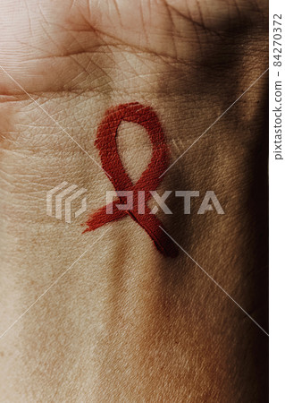 AIDS awareness ribbon painted in his wrist 84270372