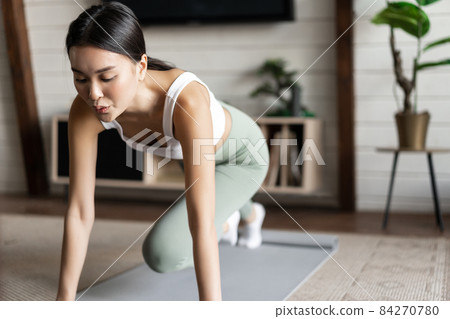 Portrait of woman workout at home in activewear, standing on fitness floor mat for exercises, wearing sportswear 84270780