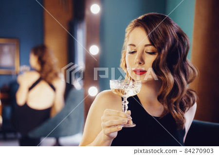 Posh elegant woman in evening dress with a glass of champagne in the luxury dressing room interior. Celebrity, superstar lifestyle. Party, drinks, holidays and celebration concept. Selective focus. Posh elegant woman in evening dress with a glass of champagne in the luxury dressing room interior. Celebrity, superstar lifestyle. Party, drinks, holidays and celebration concept. Selective focus. 84270903