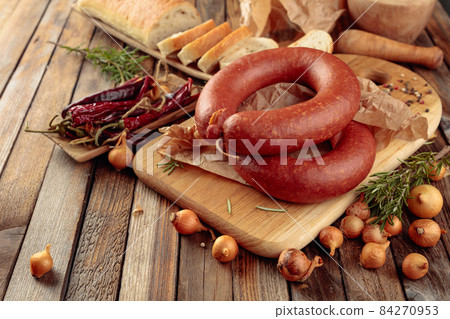 Smoked sausage with bread and spices on a old wooden table. Smoked sausage with bread and spices on a old wooden table. 84270953