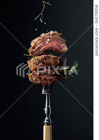 Grilled ribeye beef steak with rosemary on a black background. Grilled ribeye beef steak with rosemary on a black background. 84270956