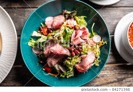 Top view of roastbeef with a colorful salad served on a turquiose plate Top view of roastbeef with a colorful salad served on a turquiose plate 84271398