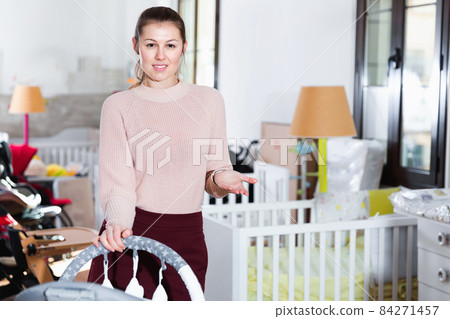 Mother buyer choosing goods in the shop of furniture for baby indoors Mother buyer choosing goods in the shop of furniture for baby indoors 84271457