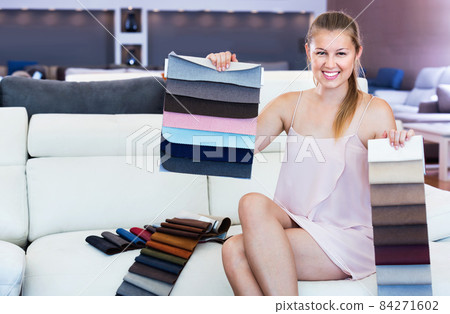 Adult female choosing quality textile on sofa in the furniture store 84271602