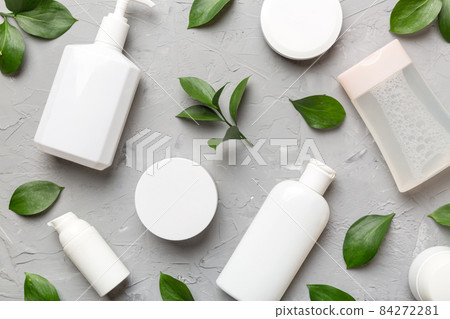 Organic cosmetic products with green leaves on cement background. Flat lay Organic cosmetic products with green leaves on cement background. Flat lay 84272281