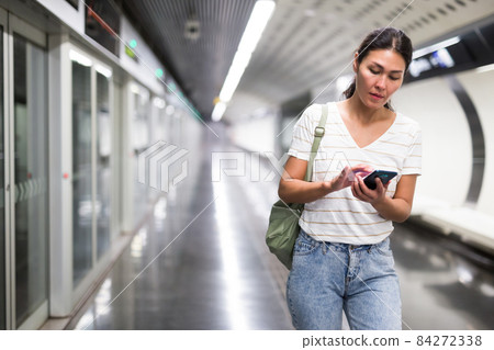 Woman using smartphone in subway station 84272338