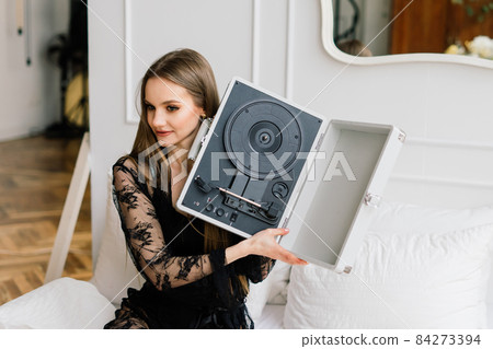 Seductive woman with beautiful long legs listening vinyl at home Seductive woman with beautiful long legs listening vinyl at home 84273394