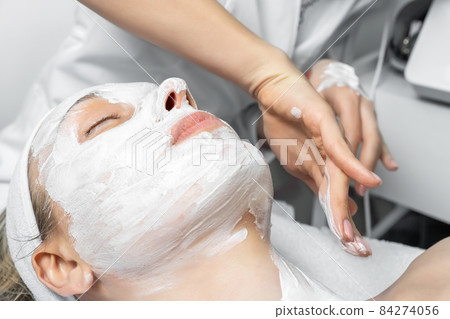 Close-up beautician doctor hand making anti-age procedure, mask and peeling for young attractive female client at beauty clinic. Cosmetologist specialist doing skincare treatment .Health care therapy Close-up beautician doctor hand making anti-age procedure, mask and peeling for young attractive female client at beauty clinic. Cosmetologist specialist doing skincare treatment .Health care therapy 84274056