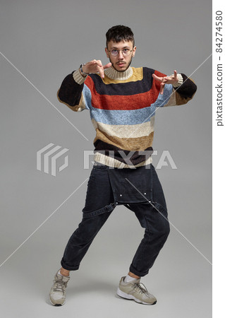 Full-length portrait of a funny guy dancing in studio on a gray background. 84274580