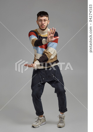 Full-length portrait of a funny guy dancing in studio on a gray background. 84274583