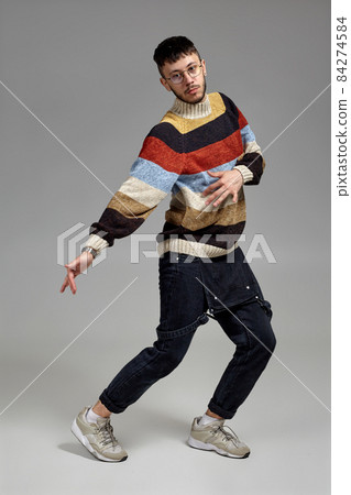 Full-length portrait of a funny guy dancing in studio on a gray background. 84274584