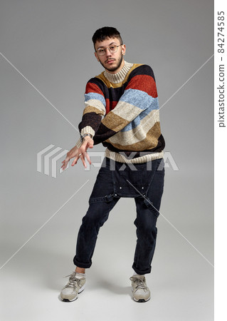 Full-length portrait of a funny guy dancing in studio on a gray background. 84274585