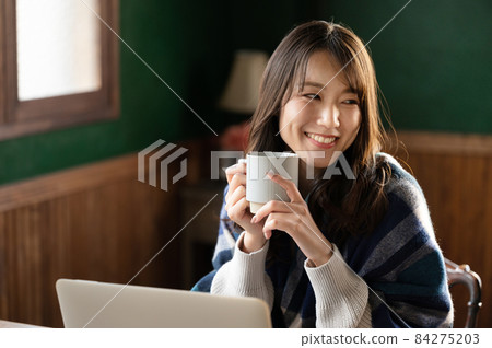 A beautiful Japanese woman relaxing with a cup of coffee with a copy space A beautiful Japanese woman relaxing with a cup of coffee with a copy space 84275203