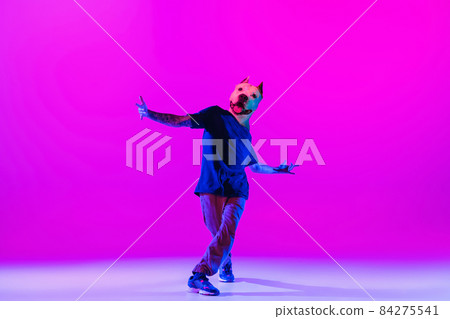 Young man, break dancing dancer headed of dog's head dancing isolated over bright magenta background at dance hall in neon light. Young man, break dancing dancer headed of dog's head dancing isolated over bright magenta background at dance hall in neon light. 84275541