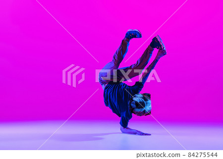 Young man, break dancing dancer headed of dog's head dancing isolated over bright magenta background at dance hall in neon light. 84275544