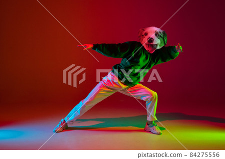 Contemporary collage. One man, hip hop dancer headed of dog's head dancing isolated over dark red background in neon light. Inspiration, idea, street dance style. Contemporary collage. One man, hip hop dancer headed of dog's head dancing isolated over dark red background in neon light. Inspiration, idea, street dance style. 84275556