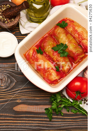 cabbage rolls stuffed with ground beef and rice with sour cream in a baking dish and ingredients 84275630