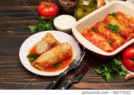 cabbage rolls stuffed with ground beef and rice with sour cream in a baking dish and ingredients 84275632