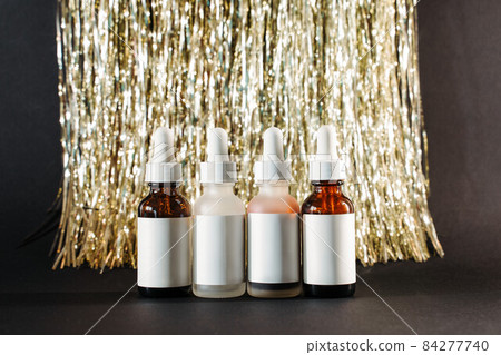 many face serums in dark and light glass bottles on tinsel lametta and black paper background many face serums in dark and light glass bottles on tinsel lametta and black paper background 84277740