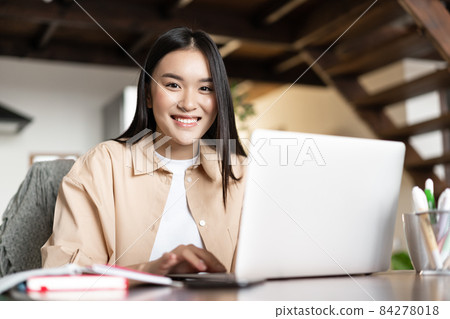 Smiling asian girl doing homework, studying online on laptop from home. Young woman working on computer pc indoors, remote work and e-learning concept Smiling asian girl doing homework, studying online on laptop from home. Young woman working on computer pc indoors, remote work and e-learning concept 84278018