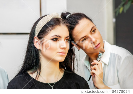 Make-up artist doing makeup for young beautiful bride applying wedding makeup in a beauty salon. Make-up artist doing makeup for young beautiful bride applying wedding makeup in a beauty salon. 84278034
