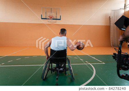 a cameraman with professional equipment records a match of the national team in a wheelchair playing a match in the arena 84278240