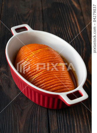 Baked hasselback pumpkin glazed with caramel in baking pan 84279837