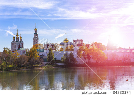 View of the Novodevichy convent (Bogoroditse-Smolensky monastery) and the big Novodevichy pond on a sunny autumn day. Moscow, Russia. UNESCO world heritage site 84280374