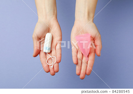 Female hands hold menstrual cup and tampon on violet background 84280545