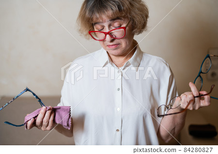 An elderly Caucasian woman chooses glasses from her home collection 84280827