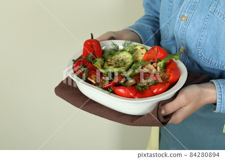 Woman hold grilled vegetables on beige background Woman hold grilled vegetables on beige background 84280894