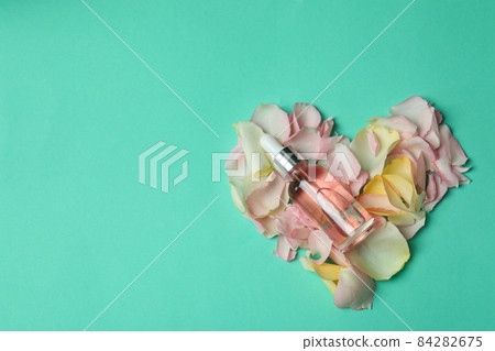 Essential rose oil and rose petals on mint background 84282675