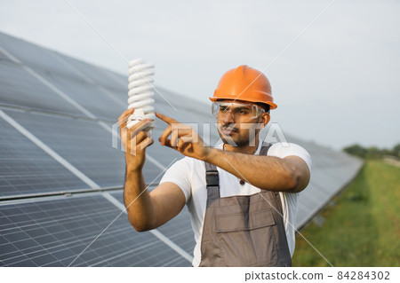 Technician man holding bulb while standing at solar station 84284302