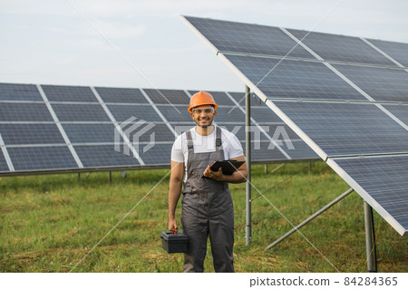 Indian engineer in uniform controlling work on solar farm Indian engineer in uniform controlling work on solar farm 84284365