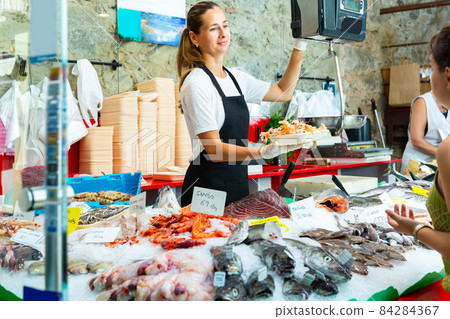 Ordinary female weighing raw prawns on scales 84284367