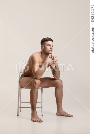 Portrait of young sad handsome shirtless man isolated on gray studio background. Natural beauty Portrait of young sad handsome shirtless man isolated on gray studio background. Natural beauty 84285173