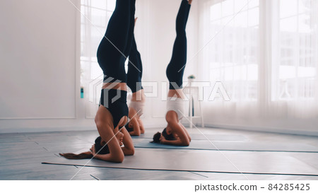 Group of Asian women stretching in yoga class. Group of girls doing Pilates exercises at the gym. 84285425